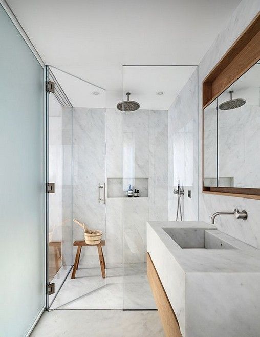 a light grey bathroom fully clad with grey large scale tiles, with touches of wood for warmth and much natural light
