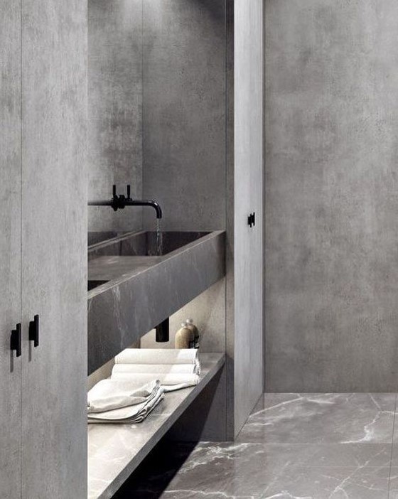 a minimalist grey bathroom done with marble, stone and concrete, with black fixtures and plenty of storage space