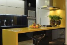 a minimalist kitchen in bold yellow and black, with glossy surfaces and lots of lights here and there