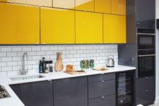 a minimalist kitchen with black lower cabinets and bright yellow upper ones plus white countertops is ultimately bold
