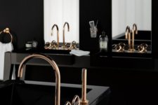 a modern refined bathroom with black sinks, a black sculptural tub, a chic blakc chandelier, gold fixtures and large mirrors