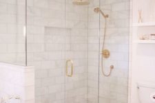 a modern white bathroom with gold framing up the shower, gold fixtures and handles and all white everything