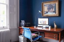 a refined blue home office with panels, a beautiful ceiling, a chic stained wooden desk, a catchy artwork