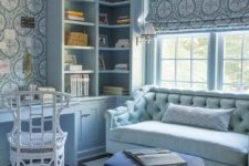 a refined light blue home office with printed wallpaper and curtains, a light blue sofa, a white chairs