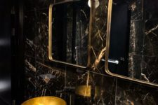 a refined powder room with black marble tiles, gold sinks, gold frame mirrors and catchy pendant lamps