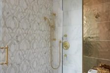 a small bathroom with neutral printed tiles, gold fixtures, a dark gold tile wall and more accents looks wow