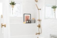 a small white bathroom with brass and gold fixtures and knobs, with a curtain rod and a gold planter to spruce up the space