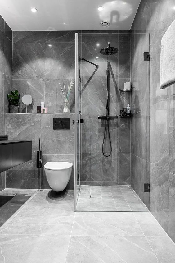 a stylish contemporary bathroom done with grey marble tiles, black fixtures and white appliaces is a chic idea