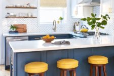 a stylish kitchen done in blue and white, with yellow stools and white countertops looks crispy fresh