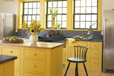a sunny yellow kitchen with black pendant lamps, a black backsplash and countertop plus black chairs for a new take on traditional decor