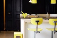 a super bold modern kitchen done with a white kitchen island, hood, black cabinetry and lemon yellow items