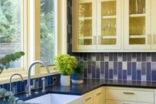 a traditional yellow and navy kitchen with navy and white tiles on the wall and backsplash