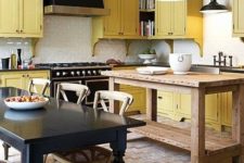 a vintage kitchen done in black, pale yellow and white, with pendant lamps and vintage and rustic furniture
