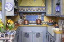 a vintage kitchen with light blue cabinets, bright yellow surfaces and mosaic tiles and plates with yellow and blue