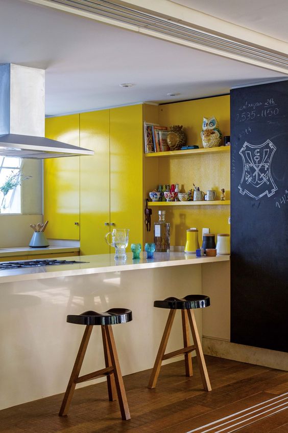bright yellow cabinetry, a chalkboard wall, black stools, a white built in kitchen island for a bold modern look