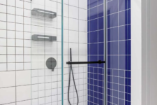 03 The bathroom is done with white tiles, black grout for achieving a graphic look and bold blue tiles for an accent