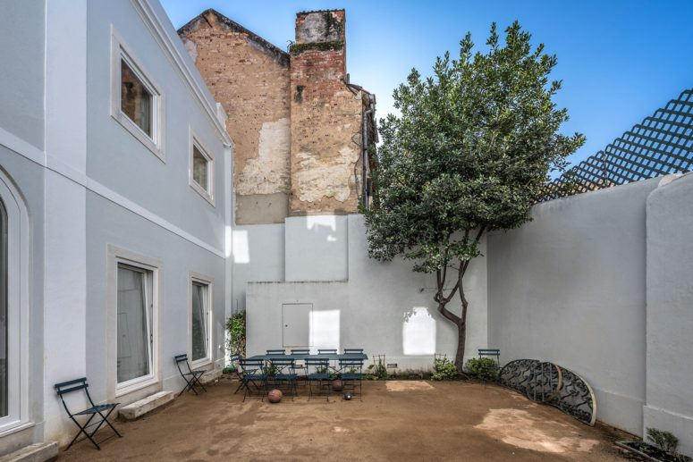 The inner courtyard features some greenery, a living tree, a simple dining set