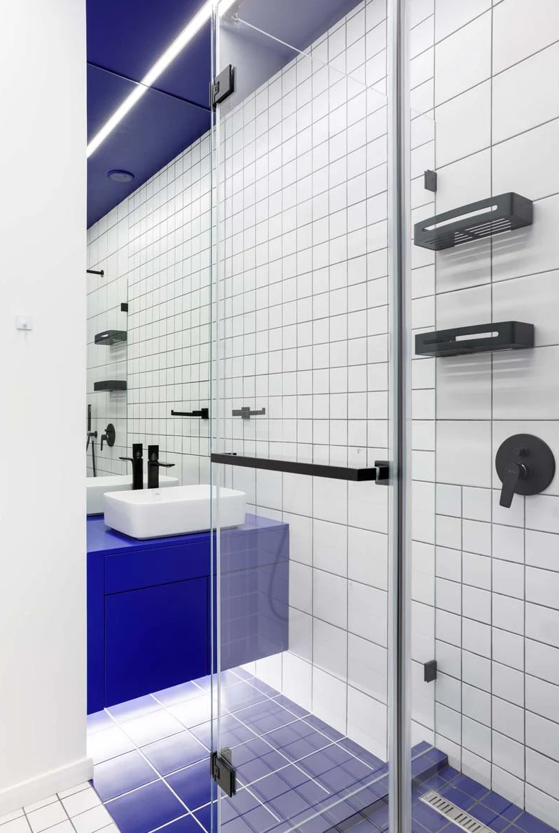 Black fixtures highlight the graphic effect and a bright blue vanity adds color