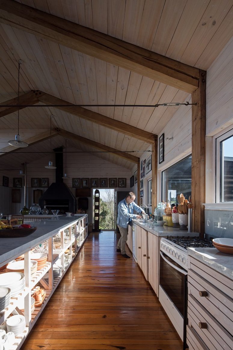 The kitchen is light-colored, clad with wood, there are lots of lower cabinets and a window for a view plus a long and large kitchen island