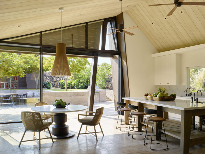 The kitchen is all neutral, and there's a small dining zone with a wooden pendant lamp