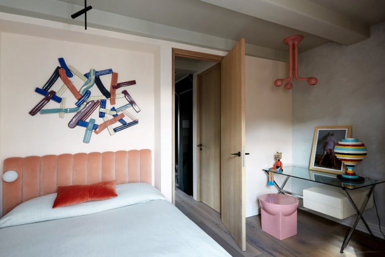 The kid's room is also catchy, with a glass desk, a pink lamp, art and a bold artwork over the bed