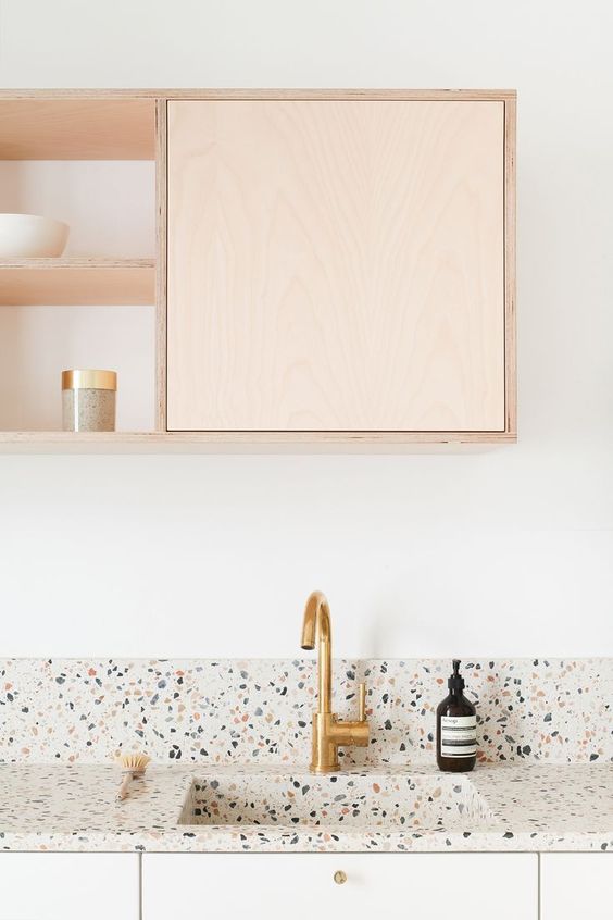 an ethereal and neutral kitchen with light-colored cabinets and a light terrazzo countertop and backsplash plus touches of gold