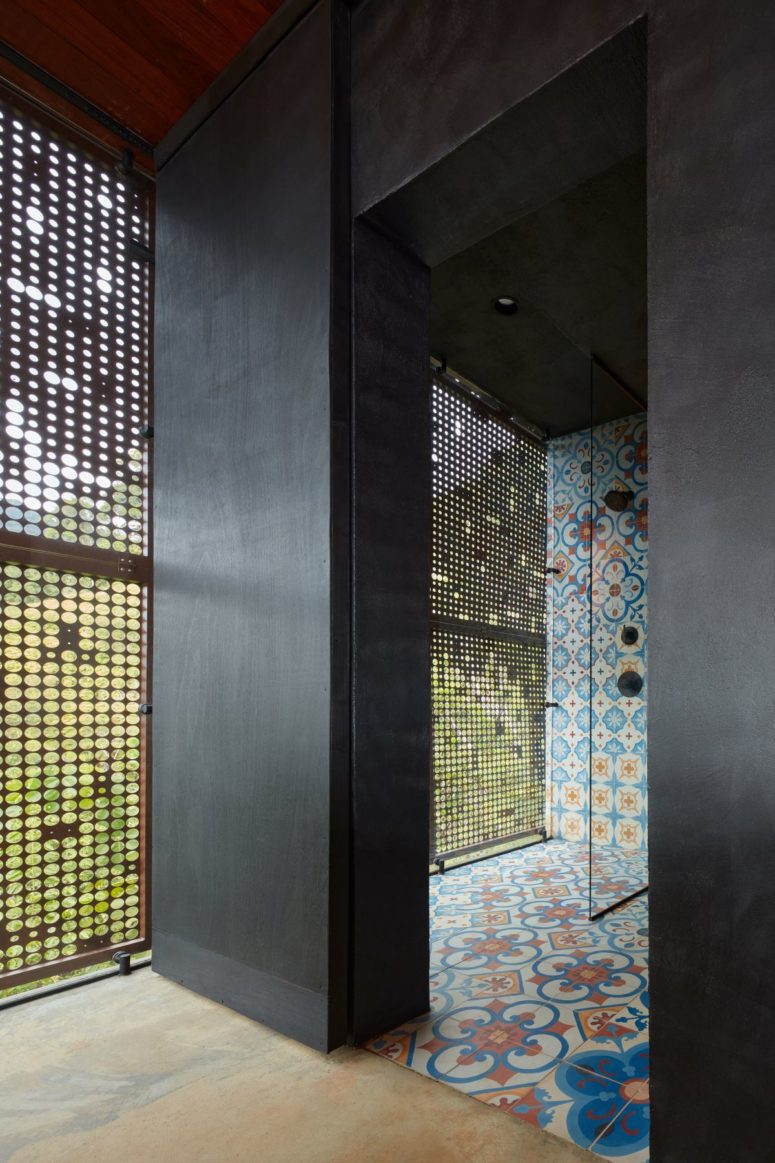 The shower spaces are done with the same bright tiles and there are perforated metal screens
