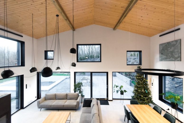 The double-height living area is framed by lots of irregular windows which bring in sunlight and beautiful views