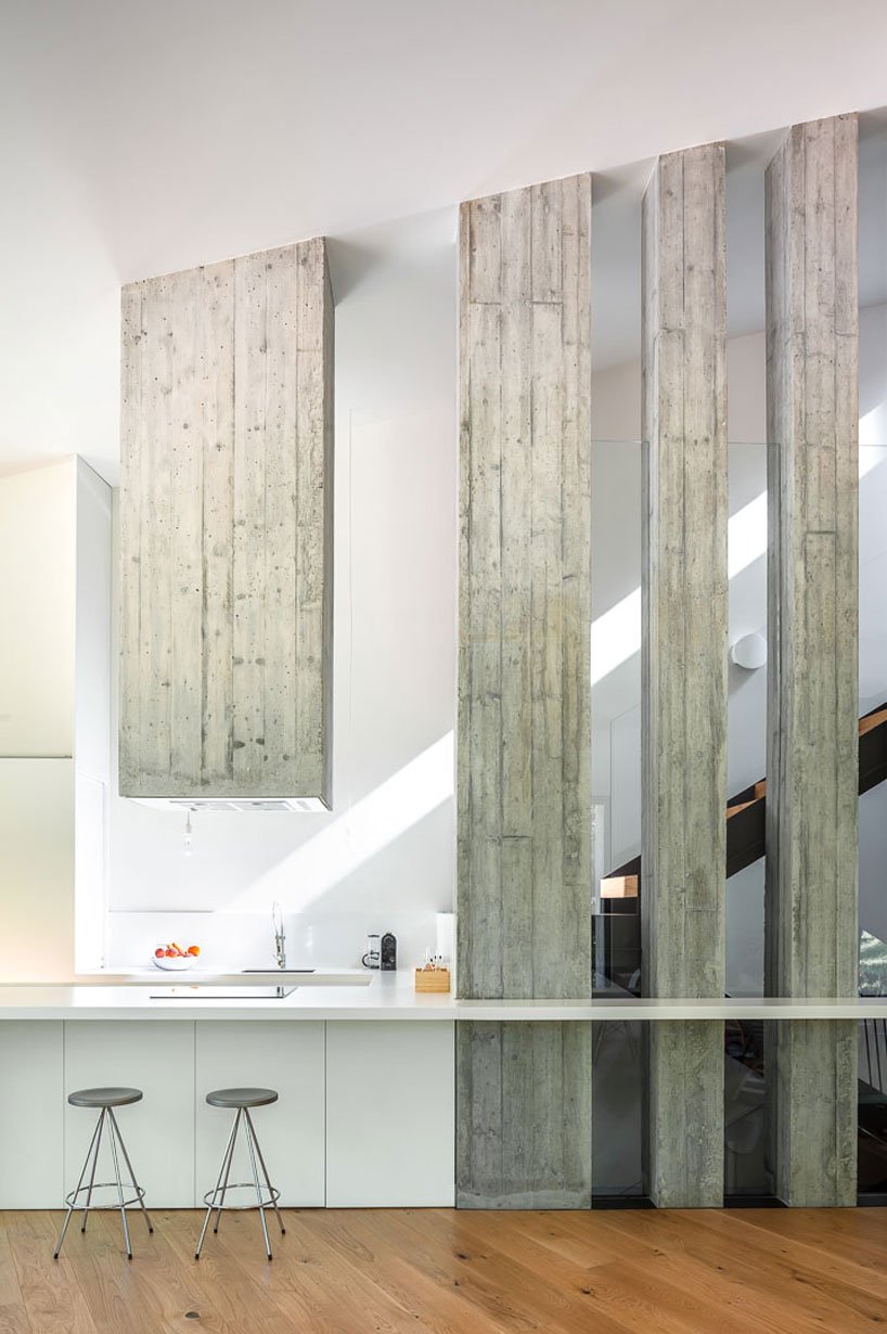 The kitchen is minimalist, with sleek cabinets, there's a whitewashed wooden hood and some beams