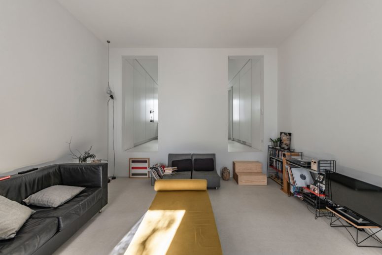 The living room is done with modern furniture that brings in some color here and open shelves