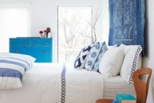 16 a bold and vivacious bedroom in white, with printed and colorful textiles, a blue tapestry instead of a usual headboard