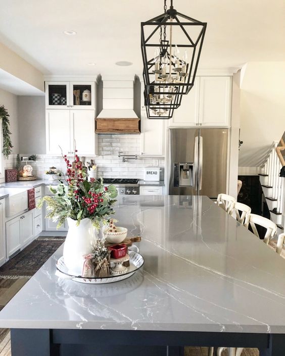 a neutral traditional kitchen with a grey marble countertop, black pendant lamps and a white subway tile backsplash