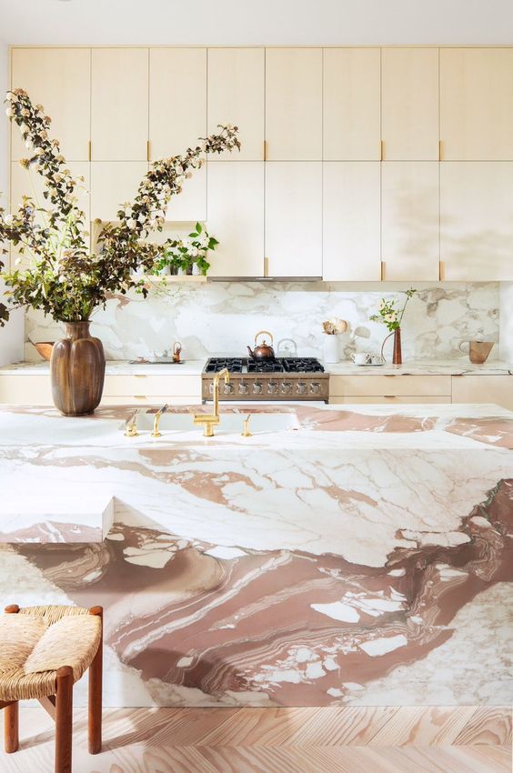 a sleek plywood kitchen with a pink marble backsplash and a gorgeous pink marble kitchen island that wows