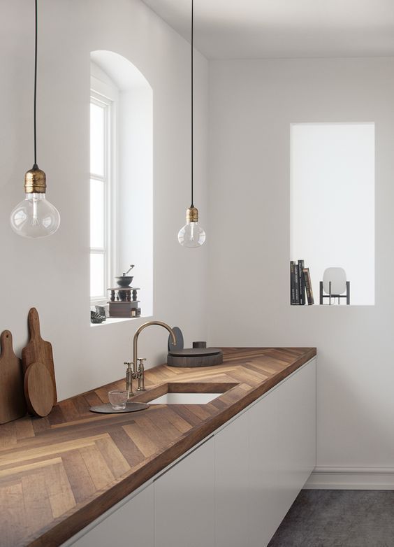 sleek white kitchen cabinets with a rich stained chevron wood kitchen countertop that brings color and texture