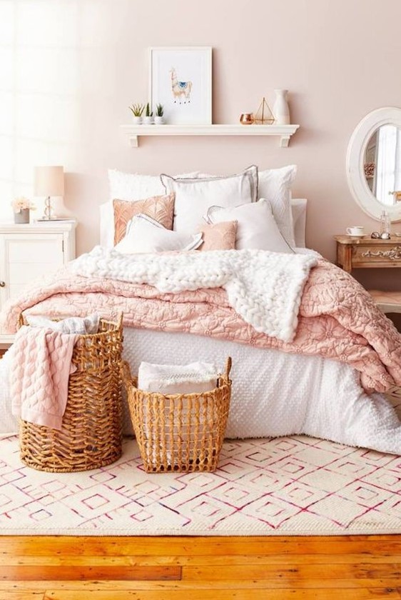 a blush bedroom with a bed with pink and white bedding, mismatching nightstands, baskets and an open shelf
