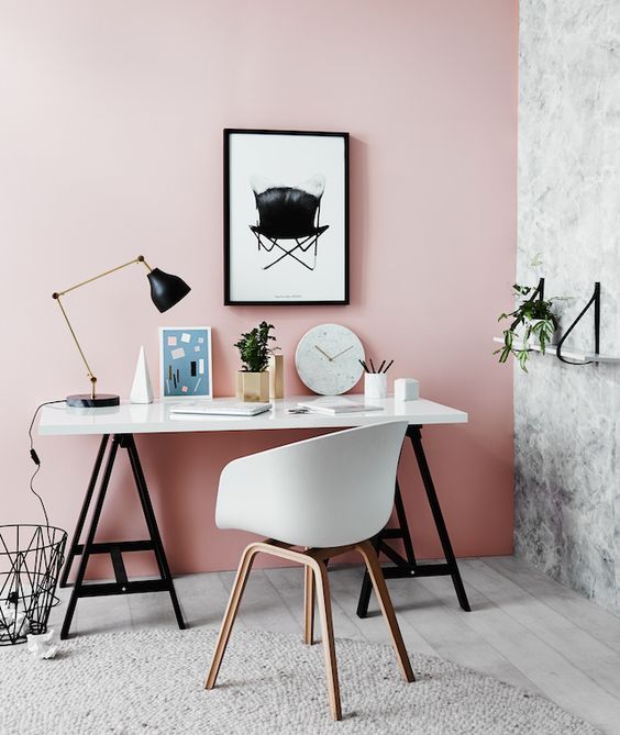 a bold home office with a pink statement wall, a marble wall, black and white furniture and a table lamp