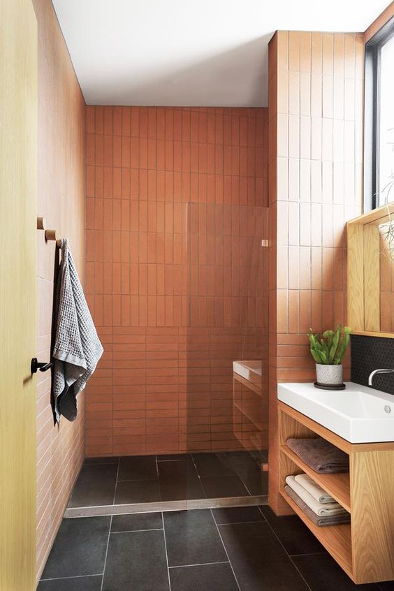 a bright bathroom with orange and yellow walls, black tiles on the floor, a stained vanity and white appliances