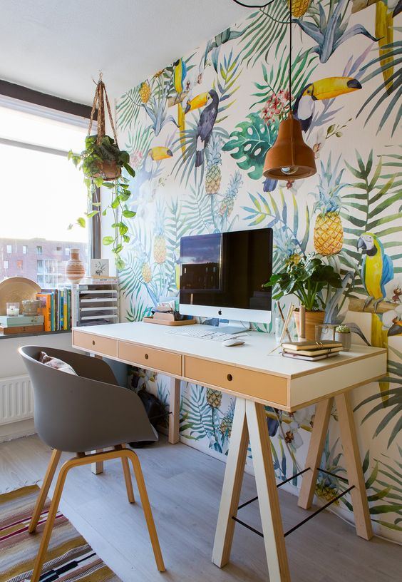 a bright tropical home office with a super bold accent wall, a cork lamp, some plants, a trestle desk and a grey chair