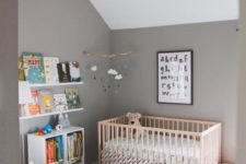 a casual nursery with grey walls and a white ceiling, a printed rug, simple furniture and a bookshelf for reading to your kid