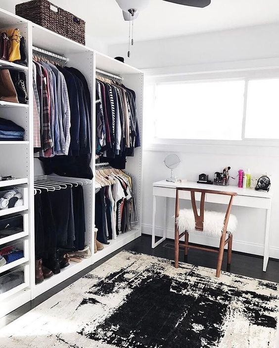 a chic monochromatic cloffice with a white desk, a wooden chair, a makeshift closet and a graphic rug