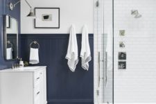 a contrasting bathroom with white tiles, navy beadboard, a skylight and printed tiles on the floor plus a white vanity