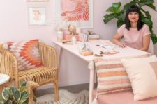 a cool glam home office with light pink walls, a pink chair, a pink gallery wall and a bright printed pillow