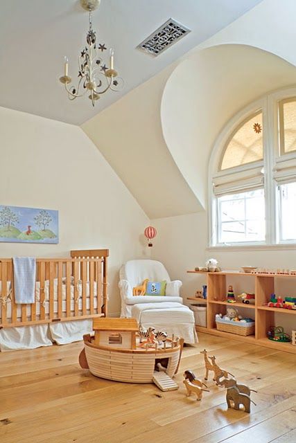 a cozy and simple attic nursery with a blue ceiling, wooden furniture, toys and a vintage chandelier