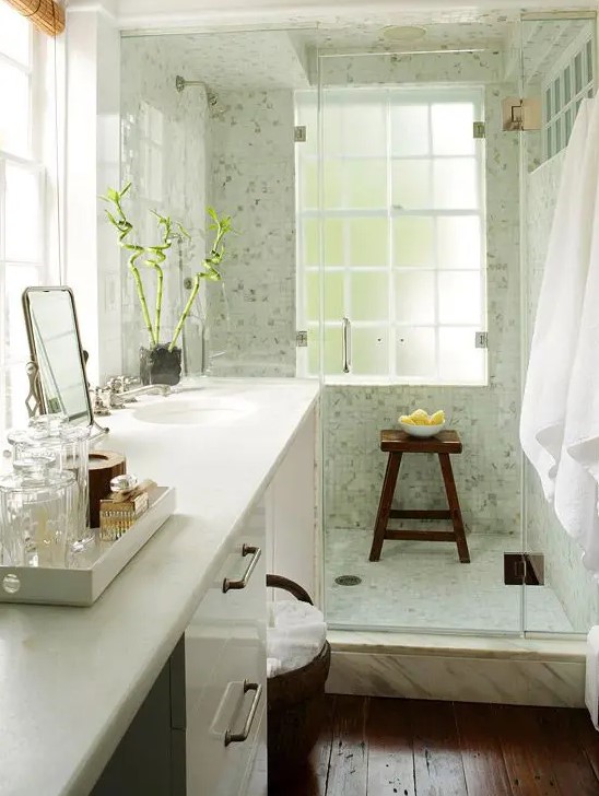 a cozy small bathroom with a large vanity and a built-in sink, a dark stained floor, a light green shower space