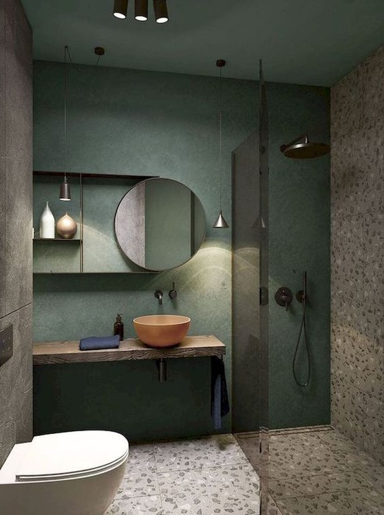 a creative small bathroom with a green wall, terrazzo flooring and wall, a wooden floating vanity and a coral bowl sink
