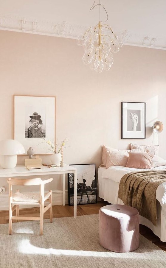 a delicate pastel pink bedroom with a bed and pink and white bedding, a lilac pouf, a white vanity, a neutral chair and a cool bubble chandelier