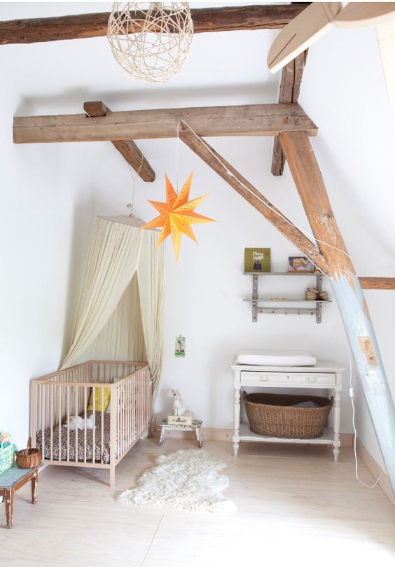 a dreamy attic nursery with wooden beams, vintage furniture, a canopy, stars and baskets plus a cute rug