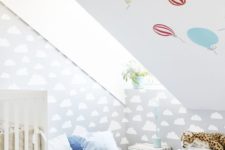a fun attic nursery with colorful pillows, a hot air balloon wall, a cloud wall and some bold toys