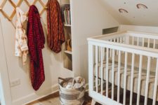 a fun nursery with a rainbow printed wall, a small crib, bright textiles and a storage unit by the bed