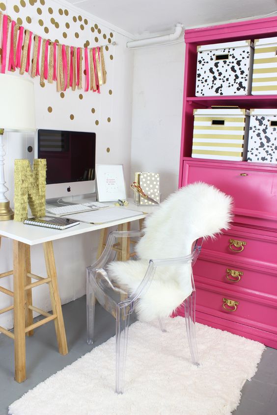 a glam home office with a hot pink storage unit and a pink and gold glitter garland plus an acrylic chair